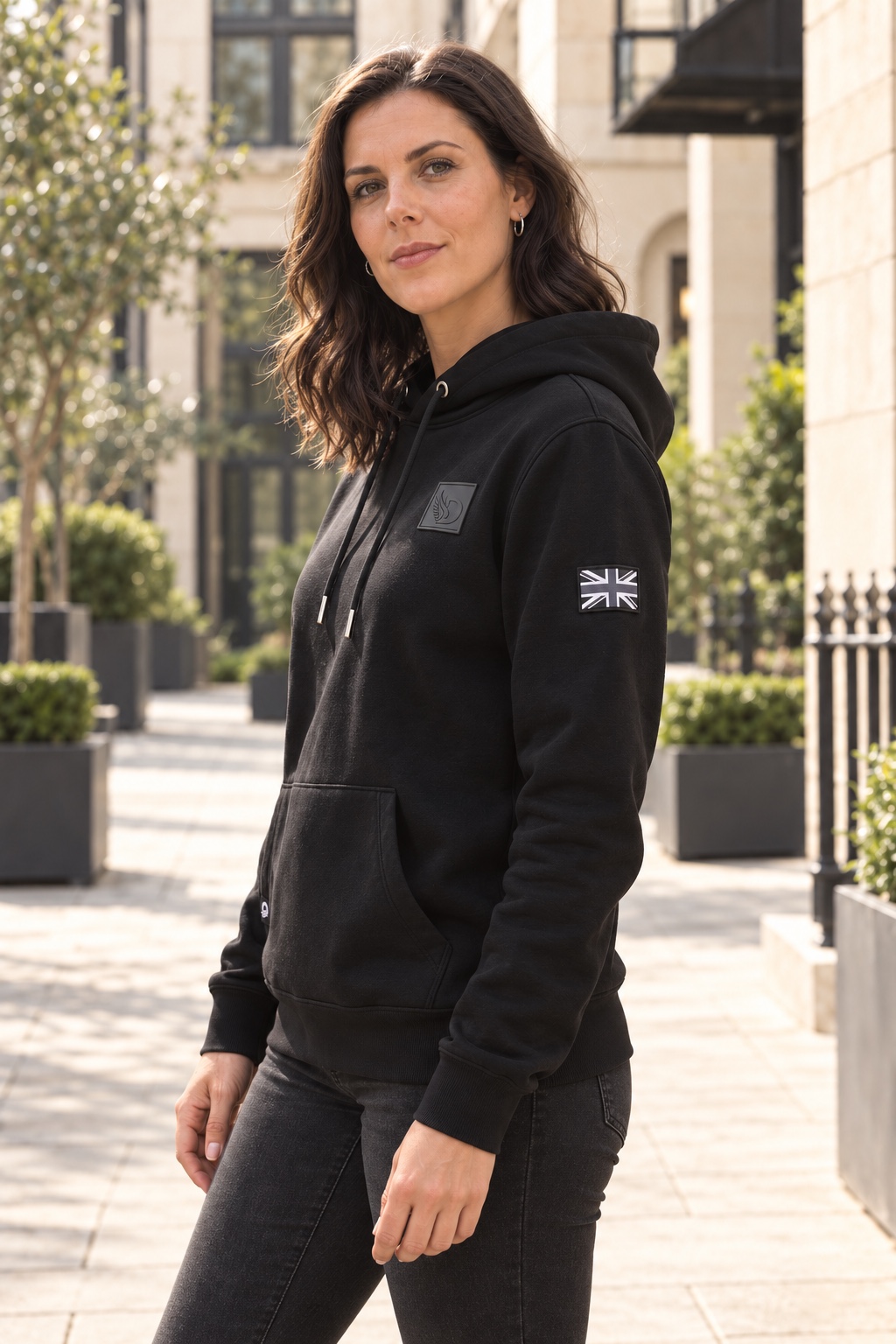 Woman wearing black DROW AJ Stealth Hoodie, side view showing Union Jack sleeve patch