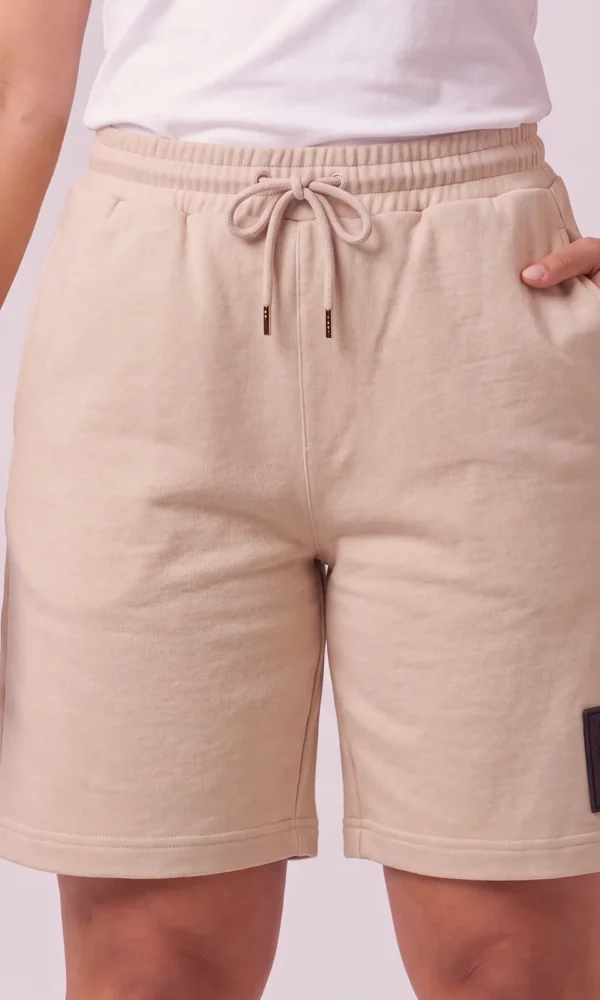 Front view of a woman wearing DROW Dust Premium Shorts with a drawcord waist, side pockets and black DROW leg patch