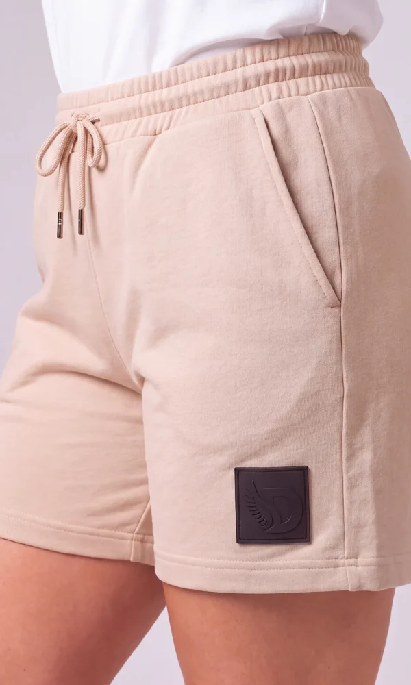 Side view of a woman wearing DROW Dust Premium Shorts with a drawcord waist, side pocket and black DROW leg patch