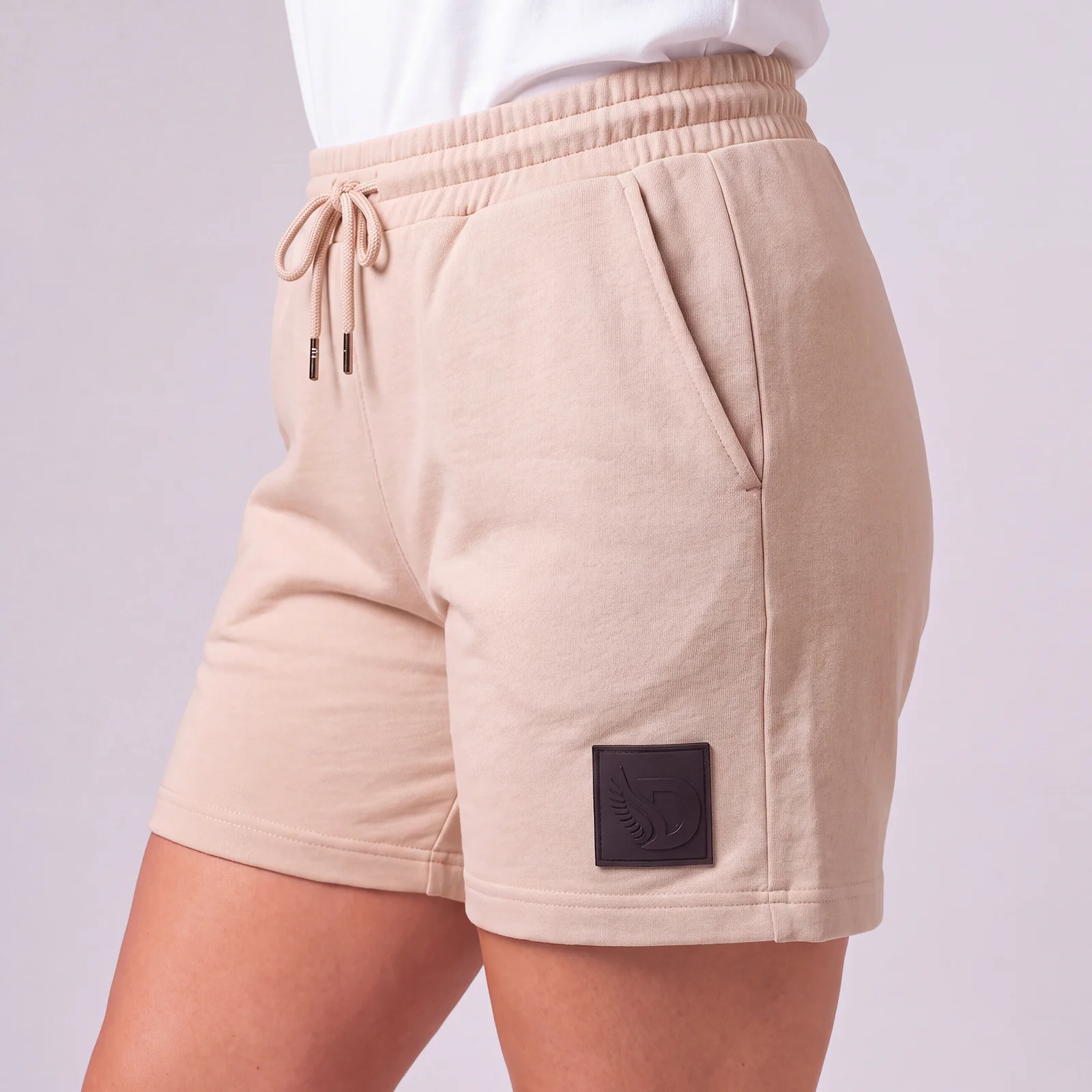 Side view of a woman wearing DROW Dust Premium Shorts with a drawcord waist, side pocket and black DROW leg patch