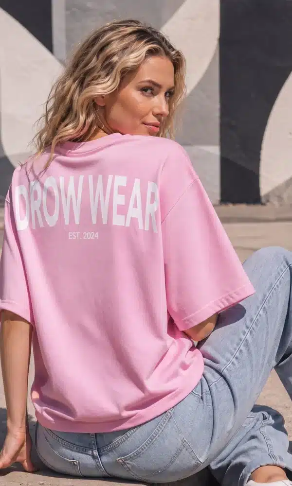 Seated woman showing the back graphic on the Fearless Pink oversized boyfriend tee