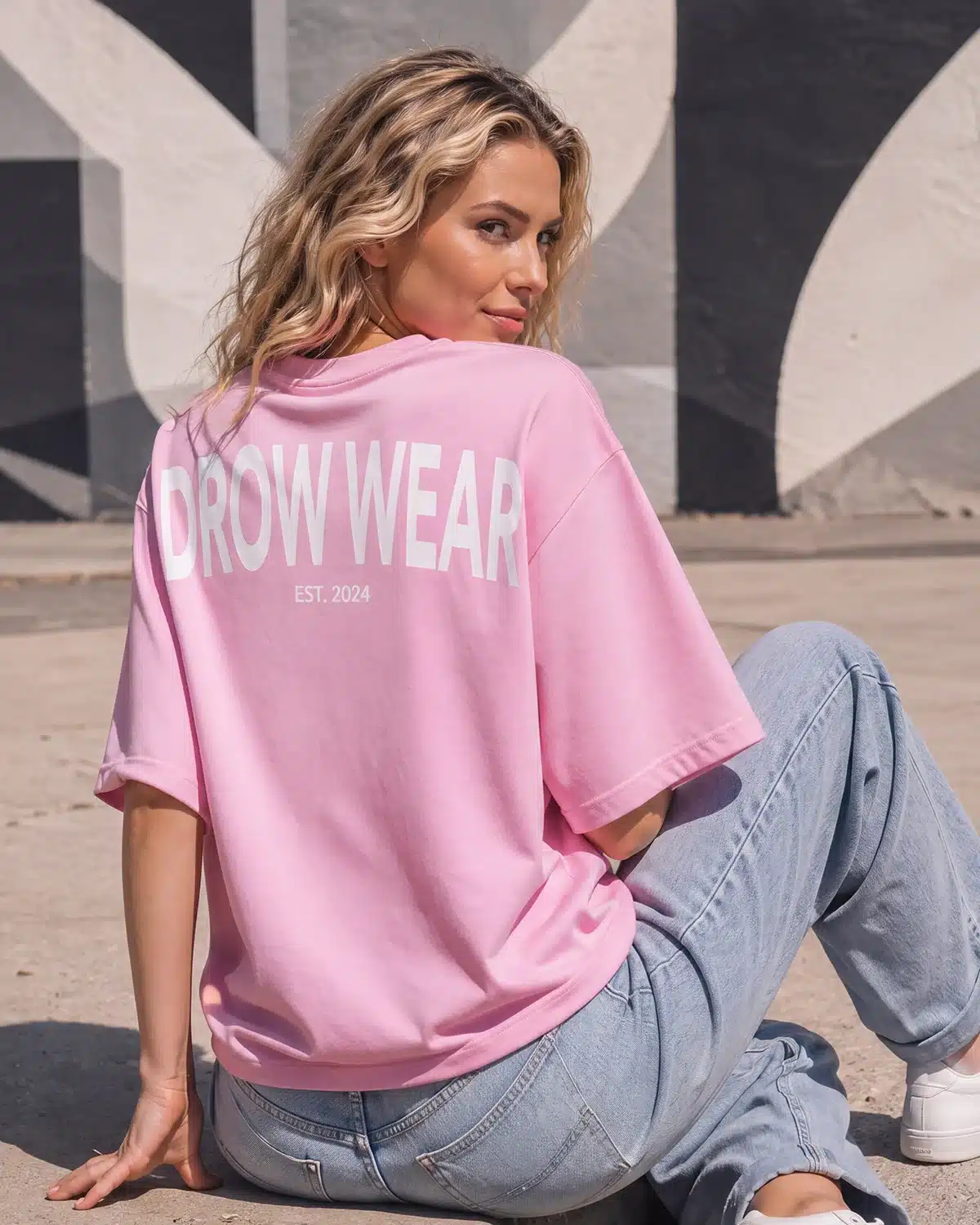 Seated woman showing the back graphic on the Fearless Pink oversized boyfriend tee